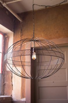 a light fixture hanging from the side of a wall next to a window in an empty room