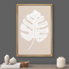 a white and gold framed art print hanging on a wall next to a table with vases