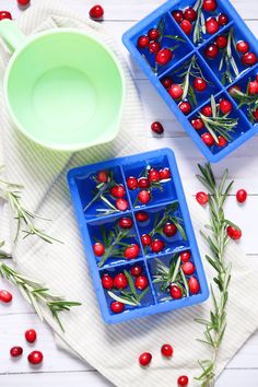 small blue trays filled with red berries on top of a white towel next to a green cup