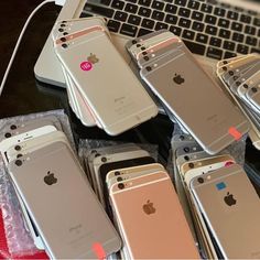 several iphones are lined up next to each other on a table near a laptop