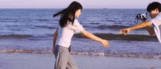 two people are playing on the beach with their hands in each others's pockets