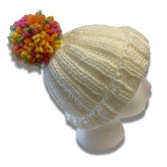 a white knitted hat with multi colored pom - poms on it's brim