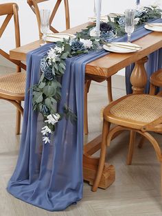 the table is set with blue linens and white flowers on it, along with candles