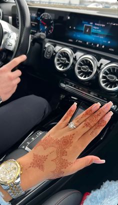 a woman with henna on her hand sitting in a car next to a steering wheel