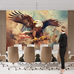 a woman standing in front of a large eagle painting on the wall above a conference room table