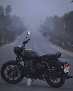 a black motorcycle parked on the side of a road in the middle of the day