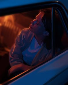 a woman sitting in the back seat of a car looking out the window at something