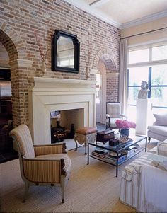 a living room filled with furniture and a fire place in front of a brick wall