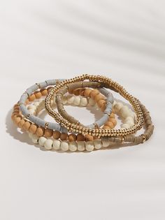 This set of five natural gold bracelets offers endless stacking possibilities, letting you personalize your style with a touch of radiant elegance. Gold Multi-strand Beaded Bracelets For Layering, Gold Multi-strand Stackable Bracelets, Gold Stackable Wrap Bracelet For Stacking, Gold Multi-strand Stackable Beaded Bracelets, Everyday Gold Multi-strand Bracelets, Stackable Wrap Bracelet For Layering, Everyday Beige Bracelet Jewelry, Bohemian Style Gold Stacked Bracelets, Bohemian Gold Stacked Bracelets