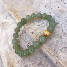 The Jade Forest Green Bracelet features pale green minerals interspersed with a 24ct gold plated brass, rustic-textured bead, creating a unique overall effect. Beyond the pleasant harmony of the colors, jade is known for its calming effect and its ability to create inner peace and harmony. The bracelet consists of 21 beads and, thanks to its elastic design, fits perfectly on an average female wrist. Handmade in our Budapest studio. MATERIAL: 24 carat gold plated brass  STORAGE/CLEANING: Store your Eva Remenyi jewellery separate from other jewellery to prevent scratches and protect gold-plating Clean with a soft cloth or a special jewellery cleaning cloth Handmade Green Jade Bracelets, Luxury Elegant Jade Bracelets, Jade Bracelet Beads, Elegant Green Jade Bracelet, Green Jade Crystal Bracelet For Meditation, Jade Jewelry Design, Hand-strung Gold Jade Bracelets, Green Bracelet, Dark Autumn