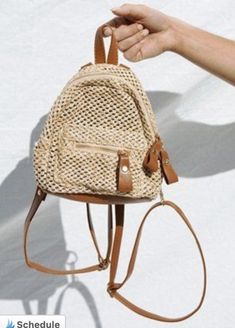 a hand holding a straw bag with leather straps