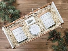 three candles in a gift box with pine cones