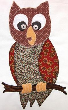 an embroidered owl sitting on top of a tree branch