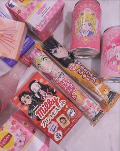 many different types of japanese candy on a white table with pink boxes and other candies