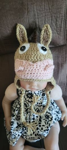 a baby doll wearing a crocheted hat and dress sitting on top of a couch