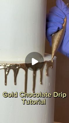 someone in blue gloves is decorating a cake with chocolate drips on the side