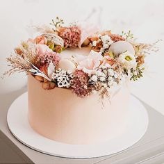 a pink cake decorated with flowers and feathers