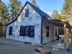 a house being built in the woods with siding on it's walls and windows