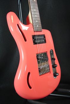 an orange electric guitar sitting on top of a black background