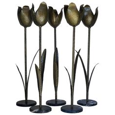 four metal flowers are standing next to each other