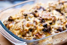 a casserole dish with mushrooms and cheese in it sitting on a wooden table