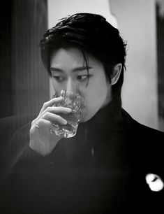 a man drinking water from a glass in front of his face