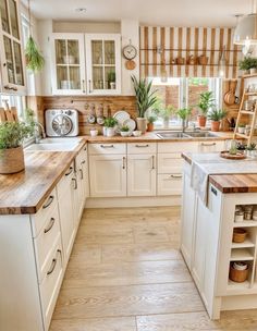 a kitchen filled with lots of white cabinets and wooden counter tops next to a window