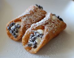 two pastries covered in powdered sugar and blueberries