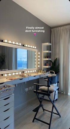 a vanity with lights on it and a chair in front of the mirror that is lit up