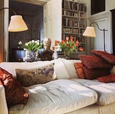 a living room filled with lots of furniture and flowers in vases on the table