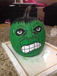 a green pumpkin with an angry face painted on it