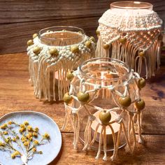 three glass vases sitting on top of a wooden table next to a white plate