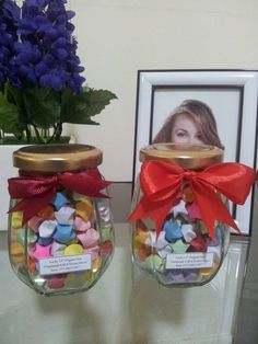 two glass jars with candies in them on a table next to a framed photo