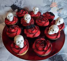 cupcakes decorated with skulls and roses on a red plate against a floral background