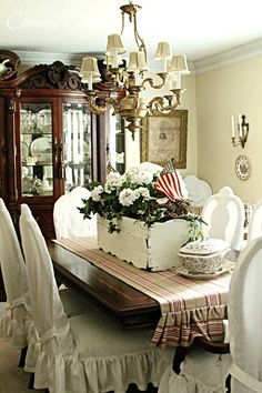 a dining room table with white chairs and an american flag centerpiece on top of it