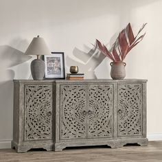 a sideboard with two vases and a plant on top