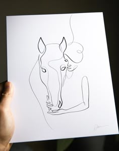 a person holding up a piece of paper with a drawing of a horse on it