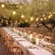 a long table is set up with candles and place settings for an outdoor dinner party