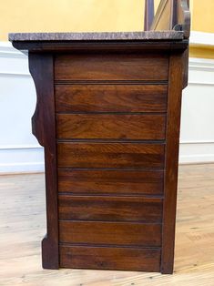 a wooden cabinet with marble top on hard wood flooring