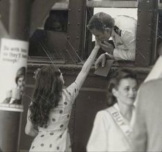 an old black and white photo of a man kissing a woman's face in front of a mirror