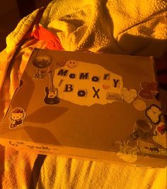 an open memory box on a bed with yellow sheets