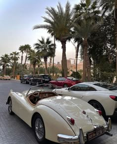 an old car is parked in front of some palm trees