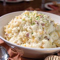 a white bowl filled with mashed potatoes on top of a table next to silverware