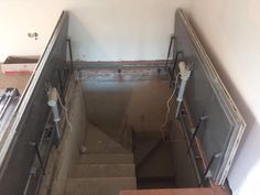 stairs leading up to the top floor in an unfinished room with exposed pipes and electrical wires