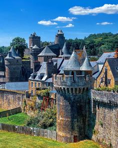 an old castle with many towers and turrets in the middle of a town surrounded by trees