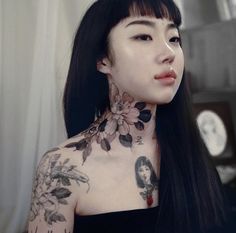 a woman with long black hair and tattoos on her neck is looking at the camera