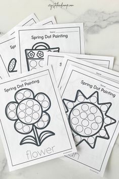 four spring dot painting worksheets on a marble surface