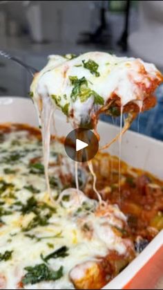 a person taking a slice of pizza from a casserole dish with cheese and spinach