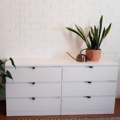 a white dresser with some plants on top