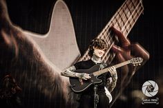 a man holding a guitar while standing on stage